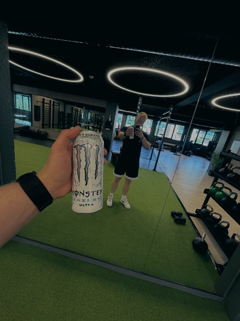 Trygve i speilet på gymmen, med en energidrikk i hånden.